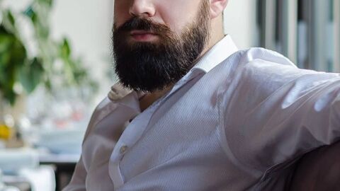 Man with beard in restaurant looking pensive
