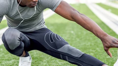 Muscular man stretching legs in gym clothing