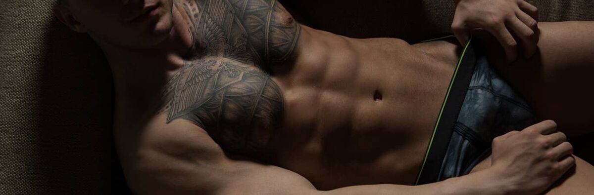Muscular tatooed man lying down with underwear on