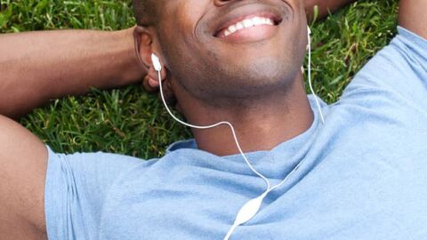 Smiling man lying on the grass with headphones