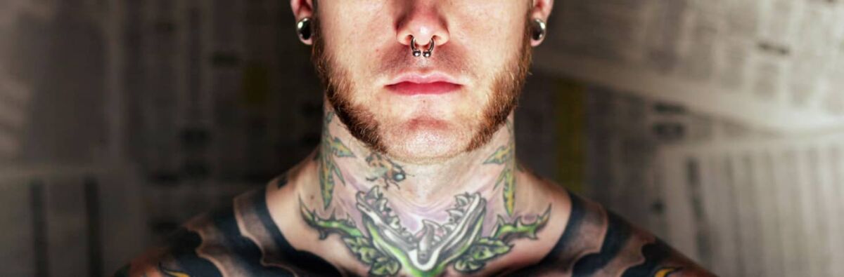 Tattooed man with nose ring and spacers and beard