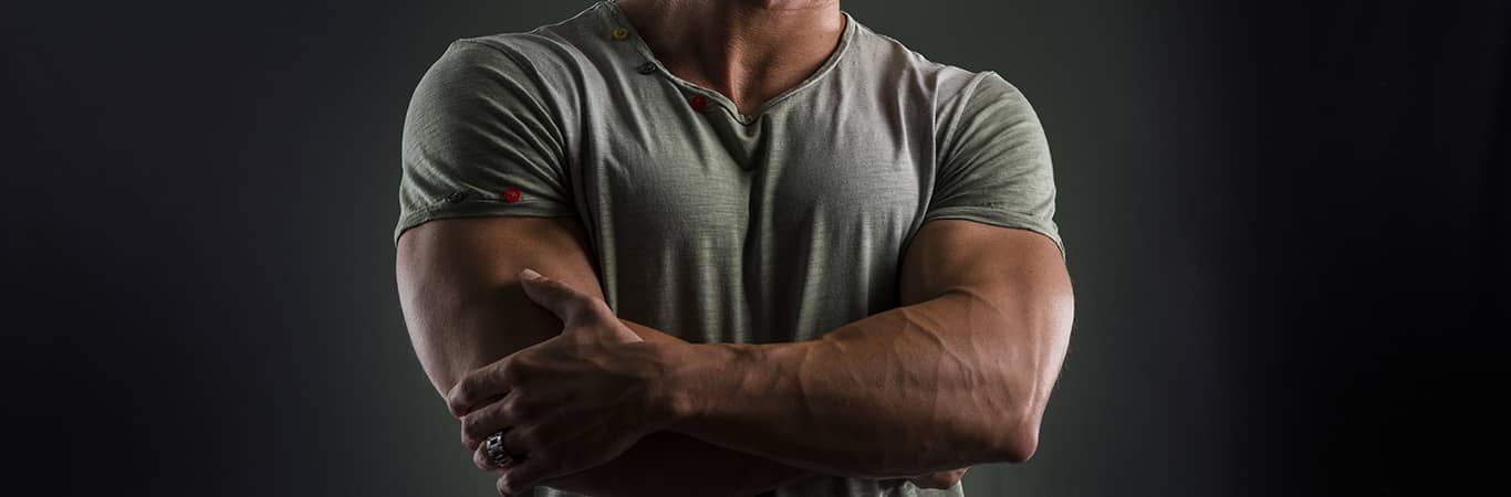 muscular gay man in grey shirt with crossed arms