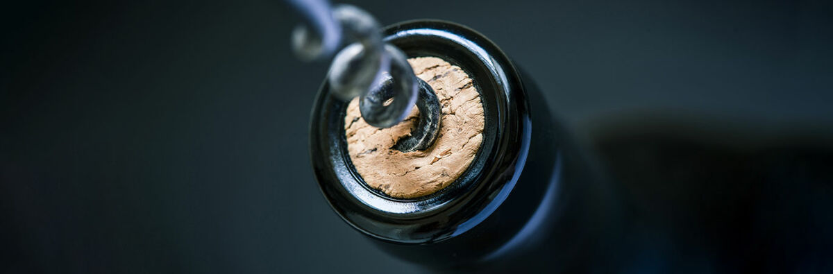 Corkscrew pulling cork from bottle of wine