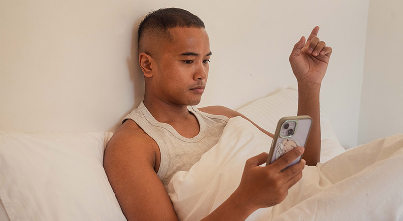 filipino-person-looking-at-phone-in-bed