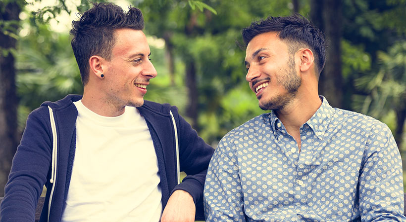 two guys on a date sitting on a park bench