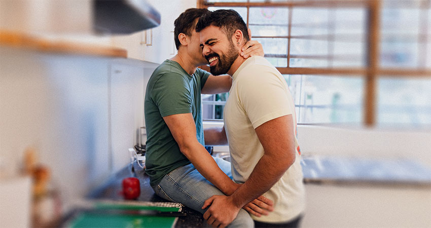 happy-venezuelan-man-kisses-south-asian-boyfriend-on-kitchen-bench