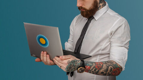tattooed man holding laptop