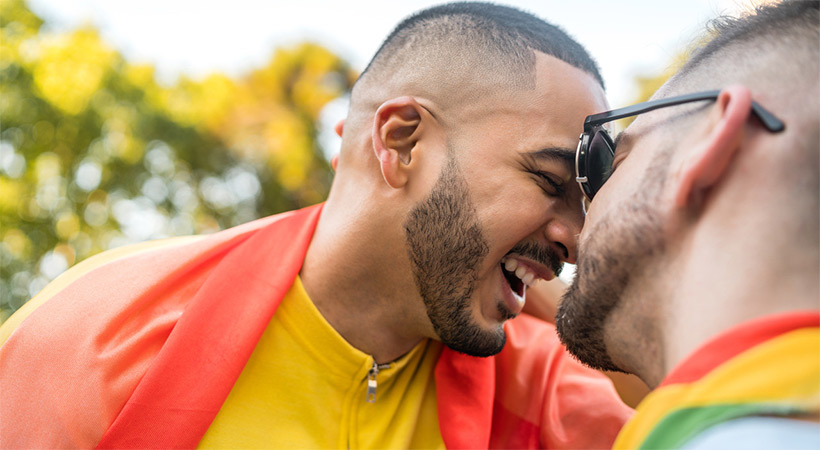 gay couple hug wrapped in pride flag
