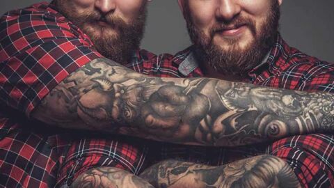 two tattood beary men hugging in checked shirts