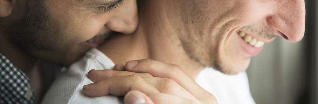 one guy hugs another guy while smiling