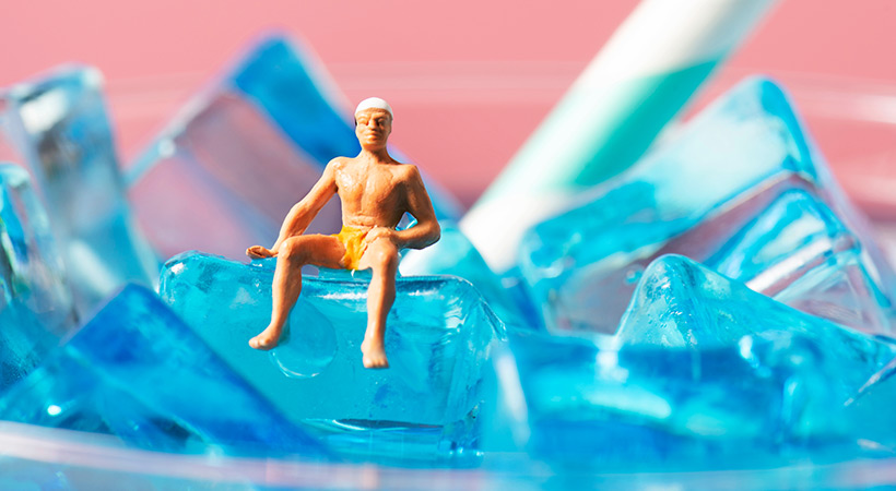 small plastic man figure sitting on top of ice cubes in drink