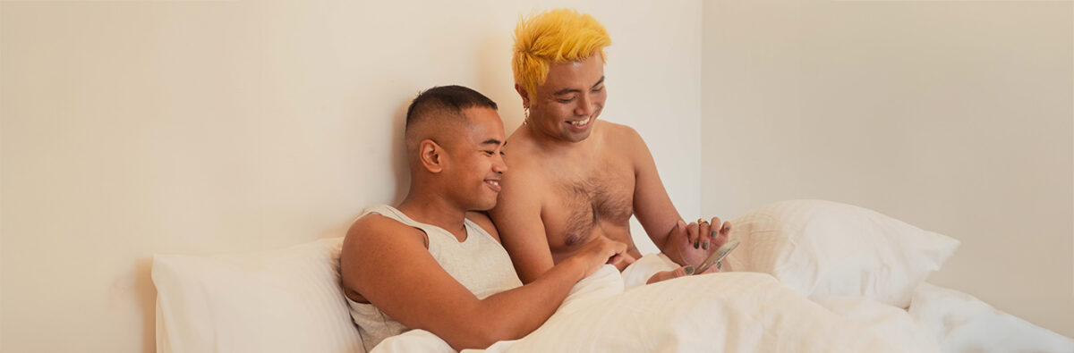 happy-asian-couple-on-phone-in-bed