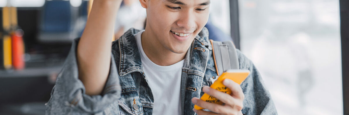 young man on bus smiles at yellow phone