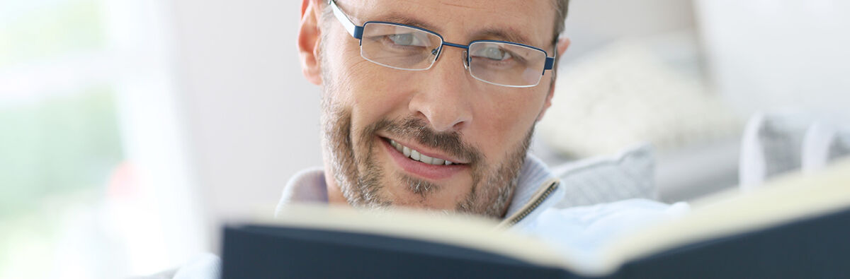 smiling man wearing glasses reading book