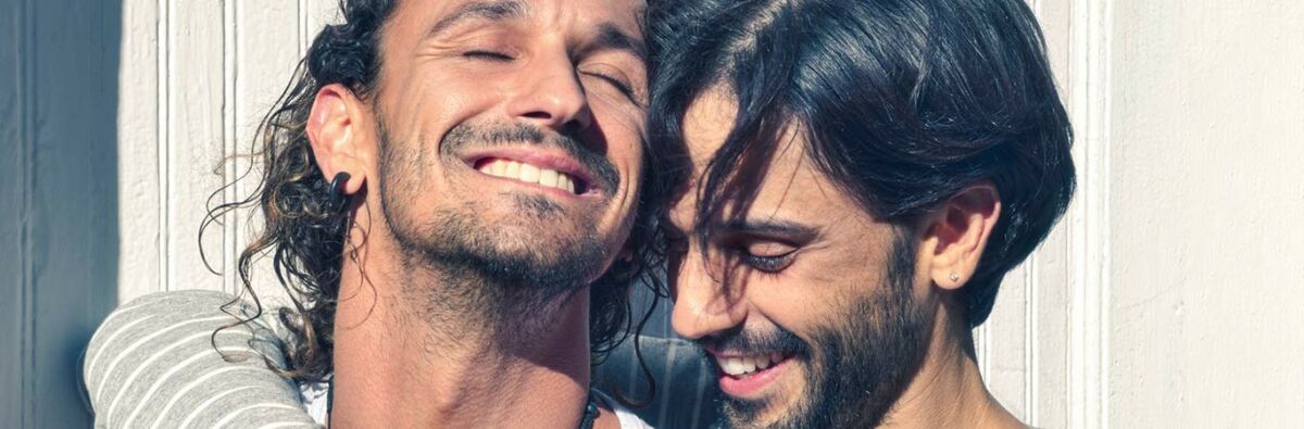 two dark haired men smiling and hugging