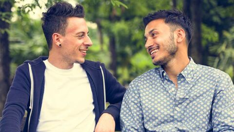 two guys on a date sitting on a park bench