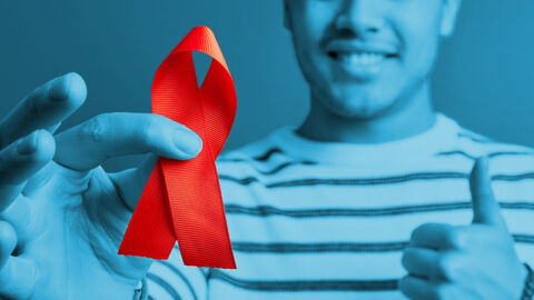 smiling man with blue overlay holding red HIV awareness ribbon for World AIDS Day