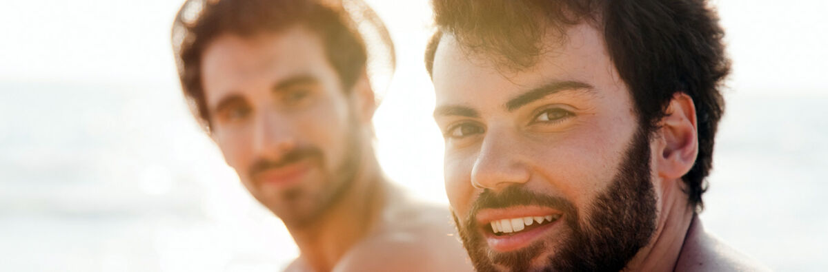 Two guys smiling and sitting by the sea