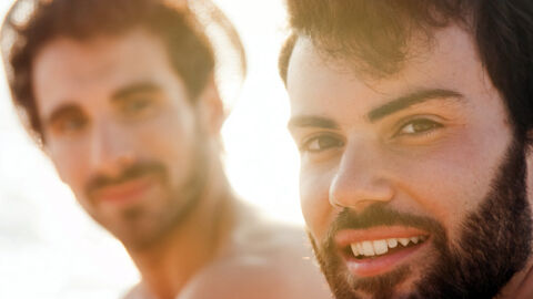 Two guys smiling and sitting by the sea