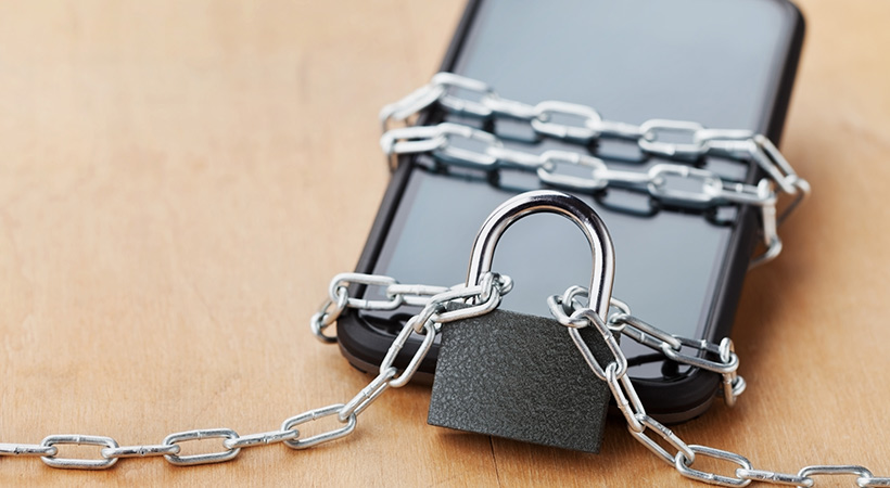 phone rests on desk wrapped in chains and secured with padlock