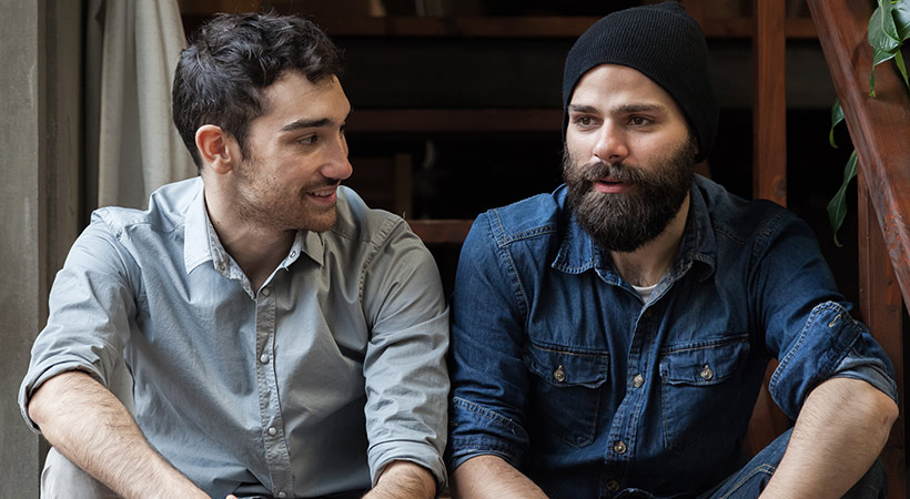 two male friends sit on steps deep in conversation