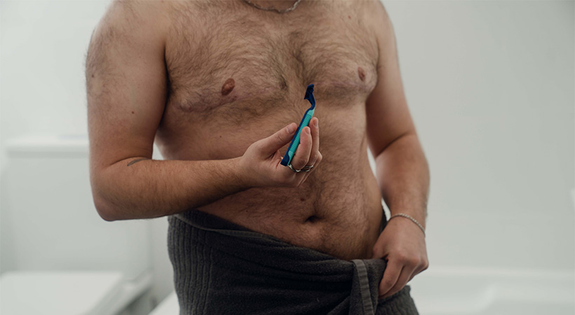 hairy-shirtless-trans-man-holding-shaver