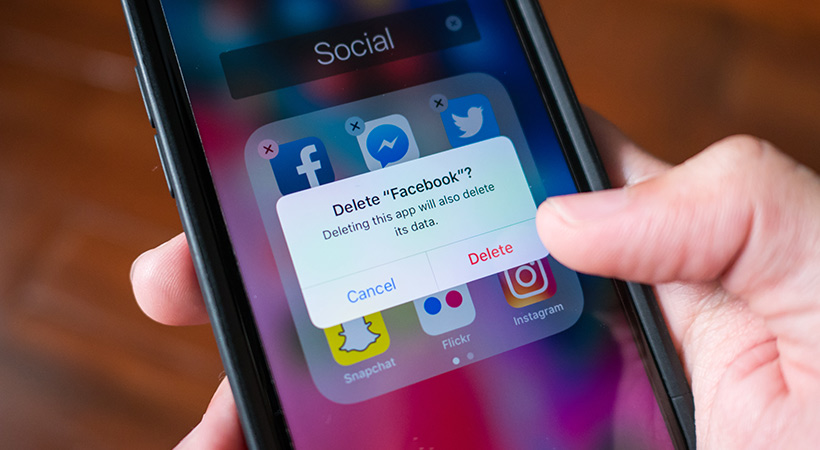 hand holding mobile phone is deleting facebook app