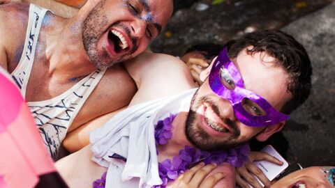 three friends dressed for a party hugging and laughing covered in glitter