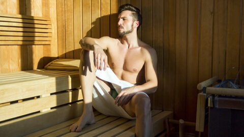 handsome man in towel relaxes at gay sauna