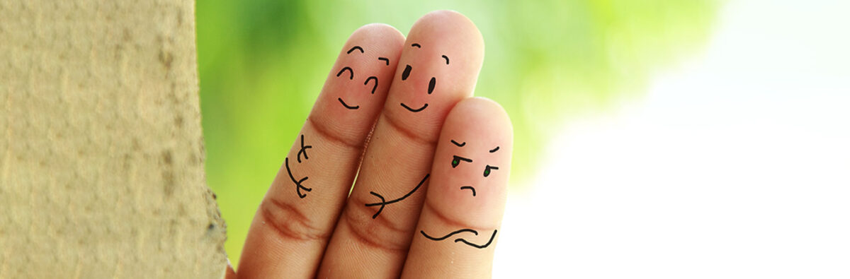 close up of three fingers with drawn on faces showing relationship jealousy