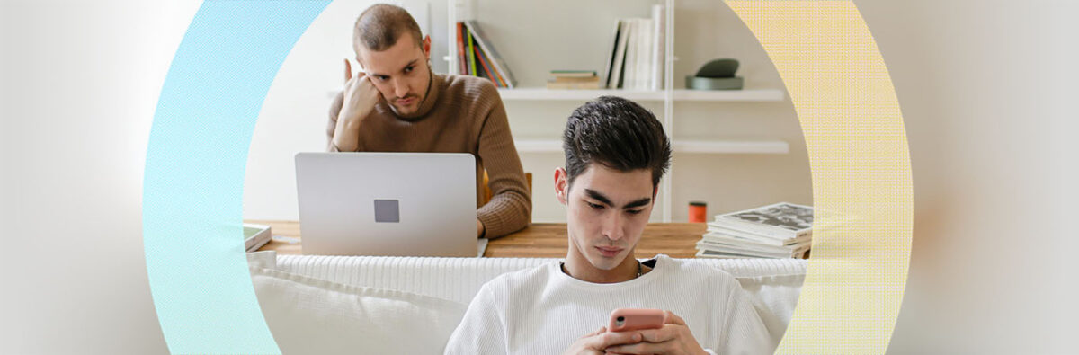 Gay couple, one on phone other looking jealous at partner. In living room with blue and yellow circle graphic.