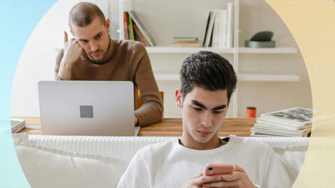 Gay couple, one on phone other looking jealous at partner. In living room with blue and yellow circle graphic.