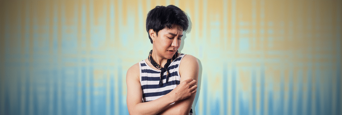 thai-man-scratching-mpox-sore-arm-blue-yellow-background