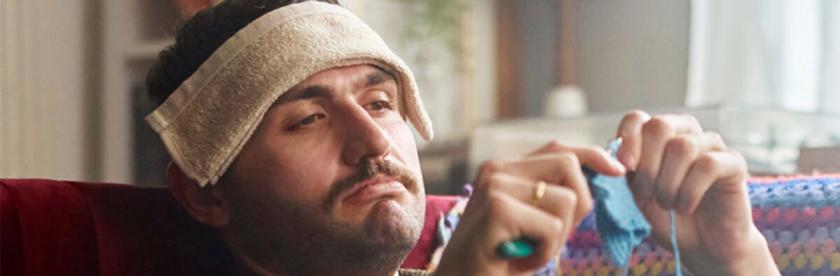 Sick white man crocheting on couch