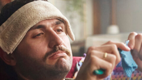 Sick white man crocheting on couch