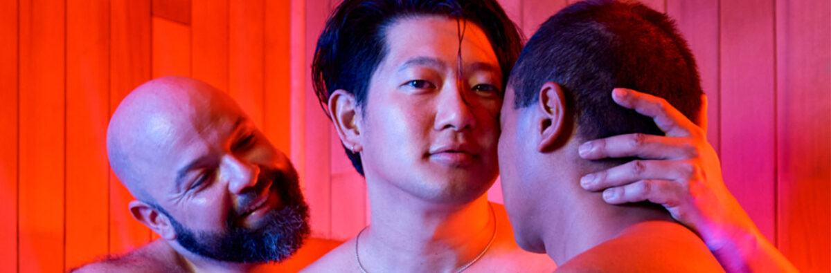 Three guys kissing in sauna with red lights