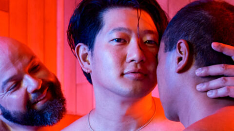 Three guys kissing in sauna with red lights