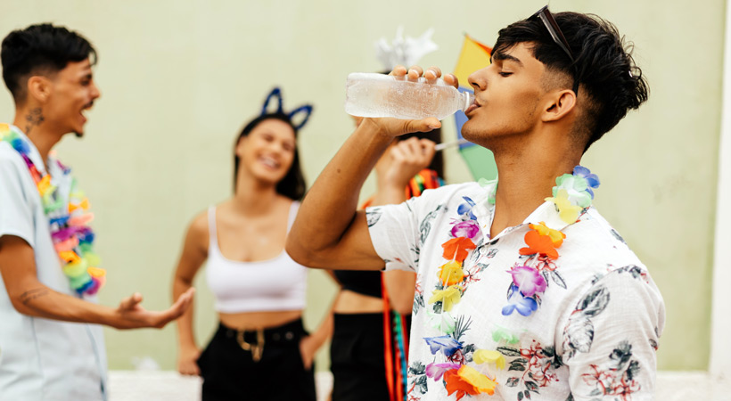 young man drinks water to rehydrate at mardi gras party