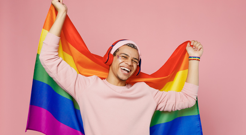 young man wears headphones and rainbow pride flag