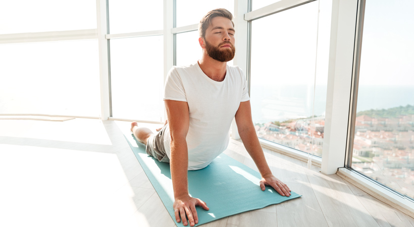 bearded man does yoga in apartment
