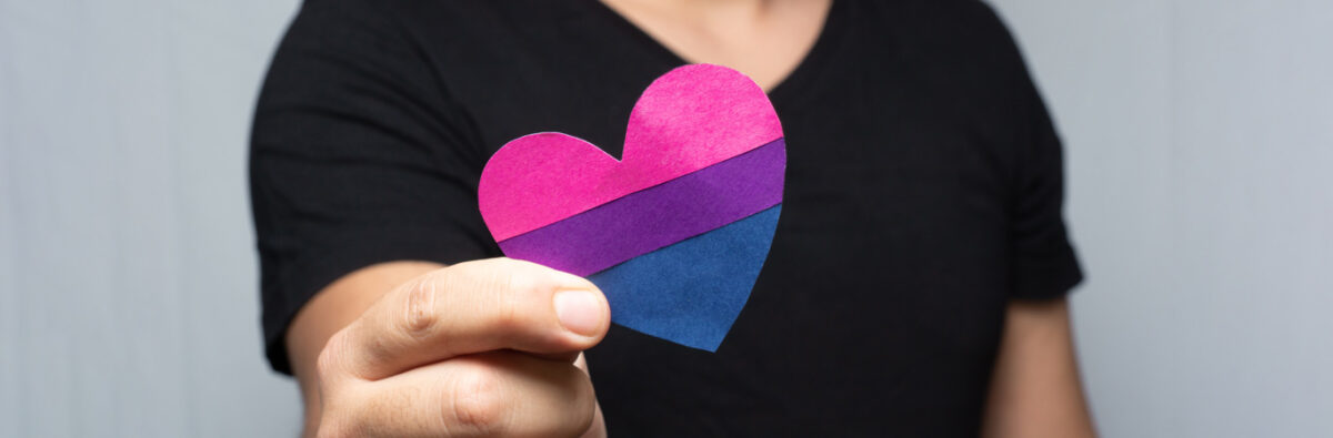 man holds heart shaped bisexual flag for bi visibility day