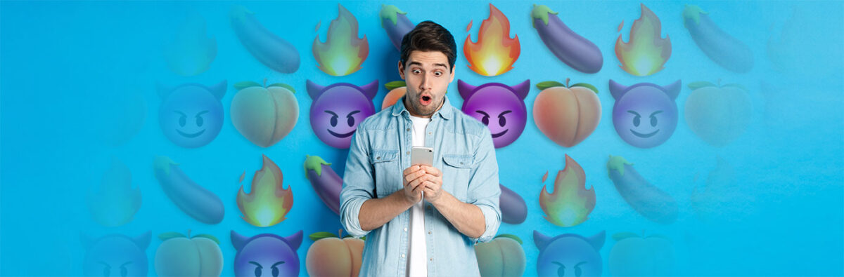 man looks in awe at his mobile phone in both hands with flirty emojis in background
