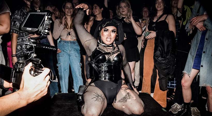 drag performer BluberryBakla performing onstage in black leather outfit