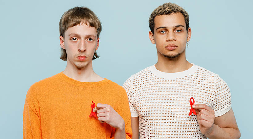 two men holding red ribbons for HIV awareness.