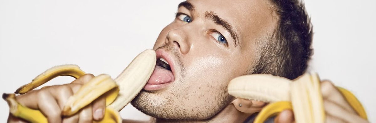 handsome young man holding a banana in both hands with his mouth open