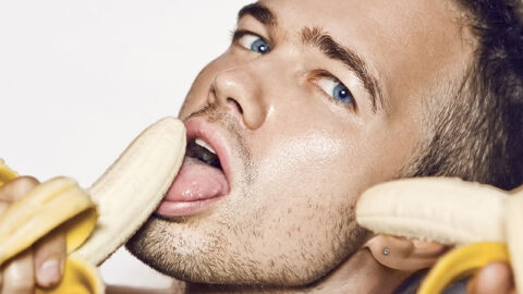 handsome young man holding a banana in both hands with his mouth open