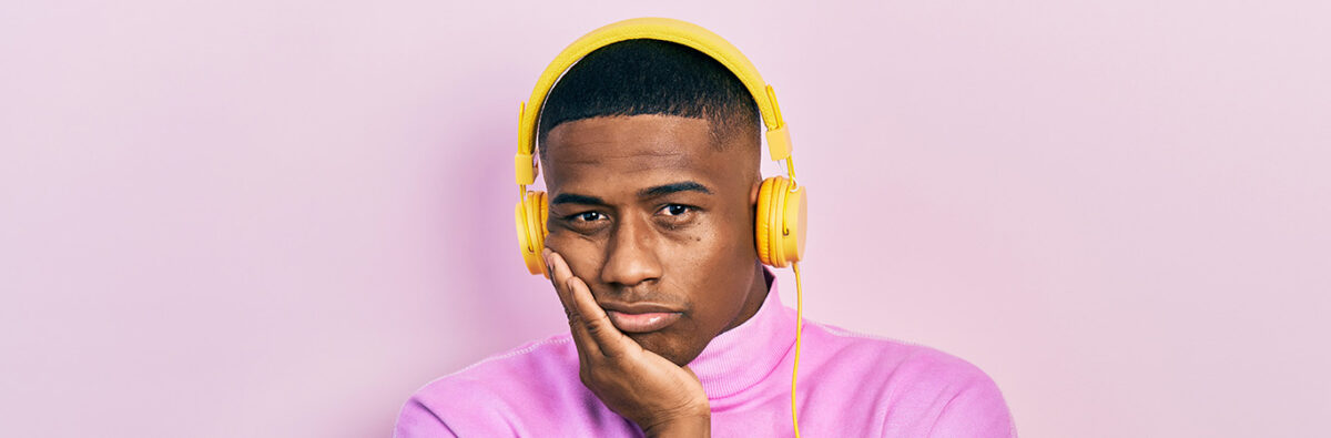 Sad black man in purple jumper and yellow headphones