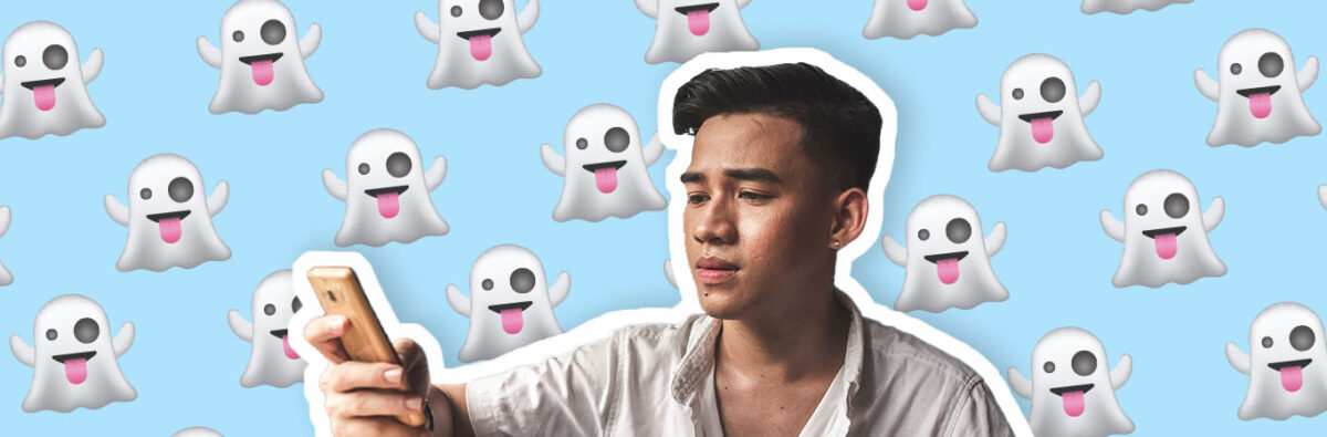 young-asian-man-looks-distressed-at-phone-with-ghosts-emoji-on-blue-background