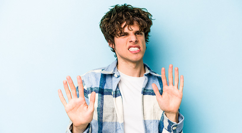 Young white man isolated on blue background rejecting someone showing a gesture of disgust.