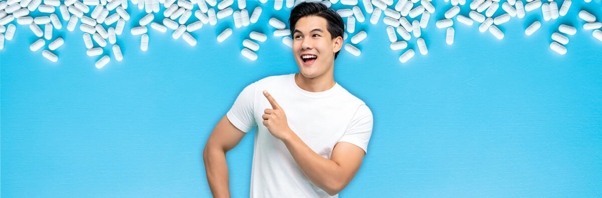 Young Asian man wearing white t-shirt excitedly taking medicine on blue background